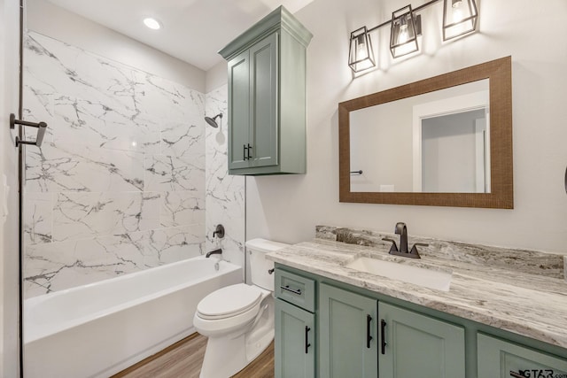 full bathroom with toilet, wood-type flooring, vanity, and tiled shower / bath combo