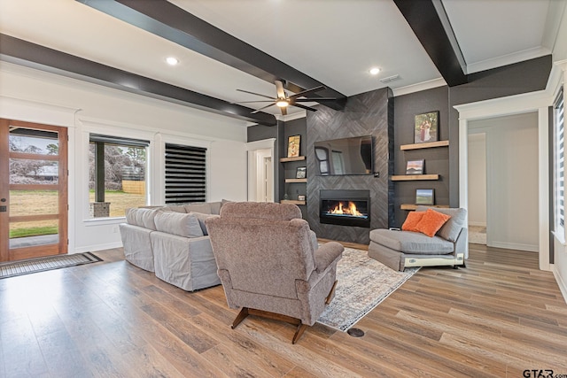 living room featuring ceiling fan, hardwood / wood-style floors, a large fireplace, and beam ceiling