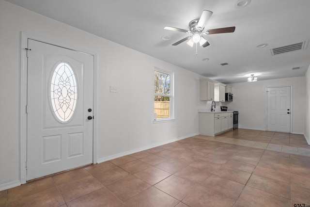 entrance foyer with ceiling fan, sink, and light tile patterned flooring