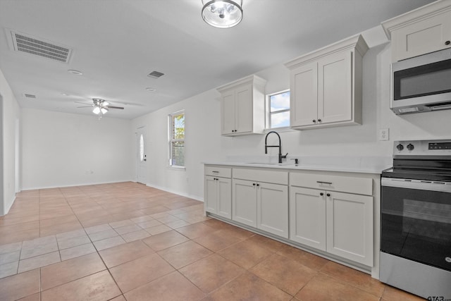 kitchen featuring ceiling fan, sink, white cabinetry, stainless steel appliances, and light tile patterned floors