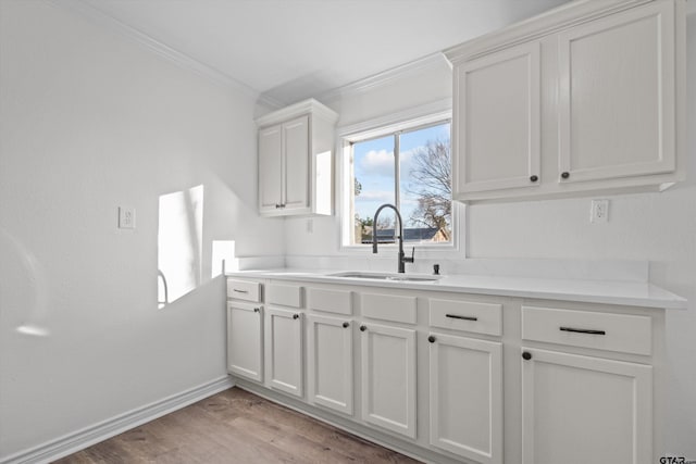 kitchen featuring ornamental molding, light hardwood / wood-style flooring, white cabinets, and sink