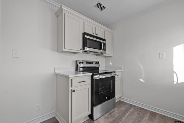 kitchen with white cabinetry, appliances with stainless steel finishes, and crown molding