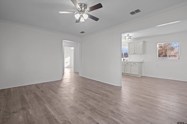 unfurnished living room with a healthy amount of sunlight, crown molding, and light hardwood / wood-style floors