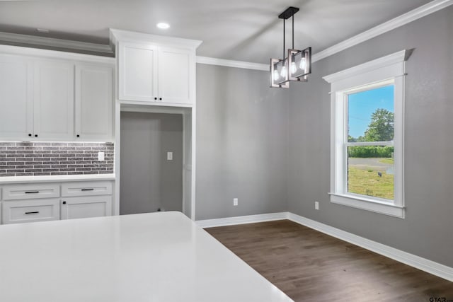 kitchen with dark hardwood / wood-style floors, backsplash, decorative light fixtures, crown molding, and white cabinets