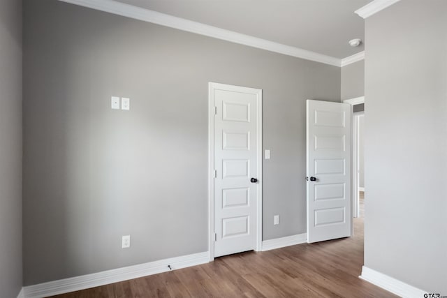 empty room with hardwood / wood-style floors and crown molding