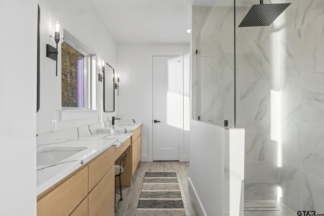 bathroom with a tile shower and vanity