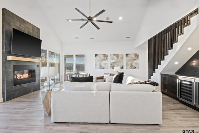 living room with ceiling fan, high vaulted ceiling, and a tiled fireplace