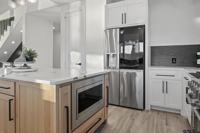 kitchen featuring light brown cabinets, stainless steel appliances, white cabinetry, and light hardwood / wood-style flooring