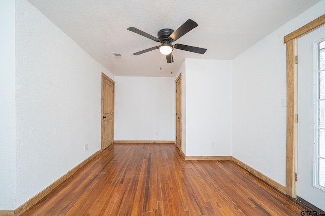 empty room featuring dark hardwood / wood-style flooring, ceiling fan, and a textured ceiling