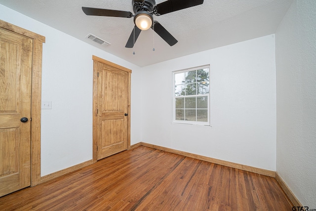 unfurnished bedroom featuring hardwood / wood-style flooring, ceiling fan, and a textured ceiling