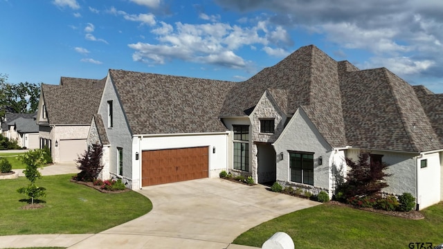 3116 Forest Ridge Cv, Tyler, TX 75703 - french country style house with stone siding, a front yard, driveway, a garage, and roof with shingles