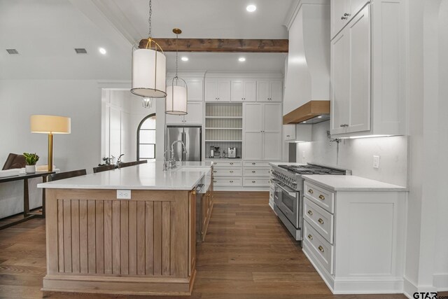 3116 Forest Ridge Cv, Tyler, TX 75703 - kitchen with high quality appliances, wall chimney exhaust hood, open shelves, dark wood finished floors, and an island with sink