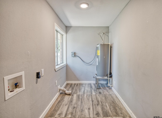 clothes washing area with water heater, washer hookup, and light hardwood / wood-style flooring