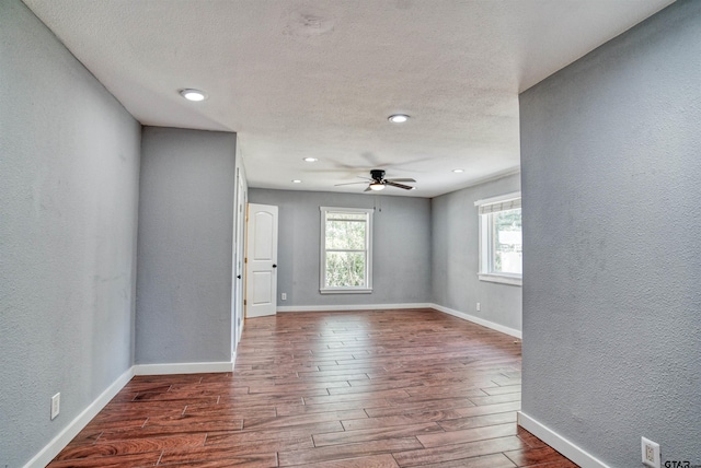 empty room featuring dark wood-type flooring, a textured ceiling, and ceiling fan