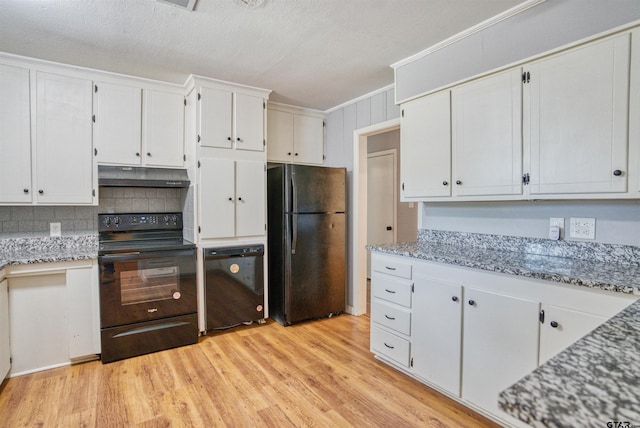 kitchen with black appliances, tasteful backsplash, light stone countertops, light hardwood / wood-style flooring, and white cabinets