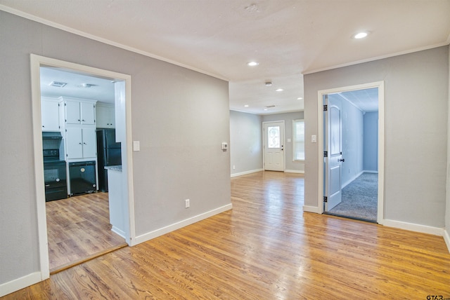 empty room with light hardwood / wood-style flooring and crown molding