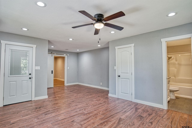 interior space with a barn door, ceiling fan, and hardwood / wood-style floors