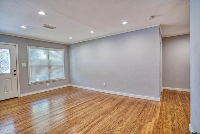 interior space featuring ornamental molding, a textured ceiling, and light hardwood / wood-style floors