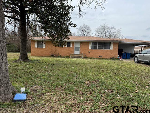 ranch-style home with a carport and a front yard