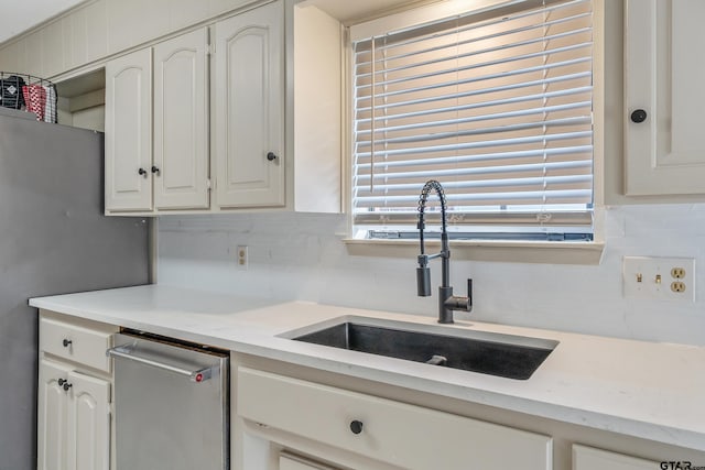 kitchen featuring stainless steel dishwasher, a wealth of natural light, sink, and white cabinetry