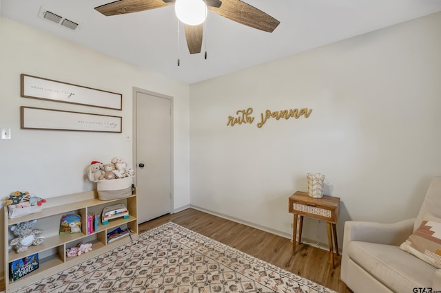 sitting room with ceiling fan and hardwood / wood-style floors