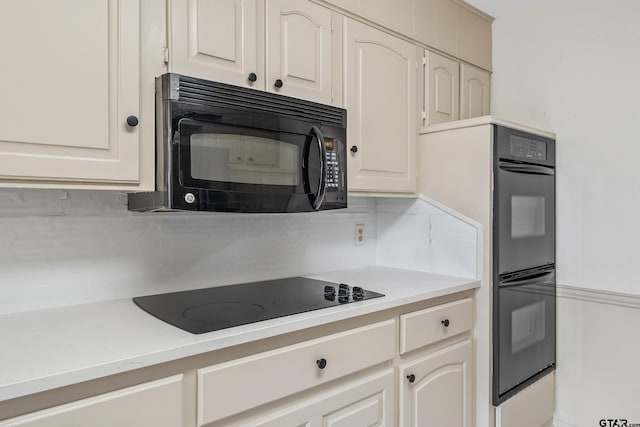 kitchen featuring backsplash, white cabinets, and black appliances