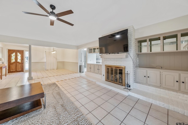 unfurnished living room featuring ceiling fan, light tile patterned floors, and a fireplace