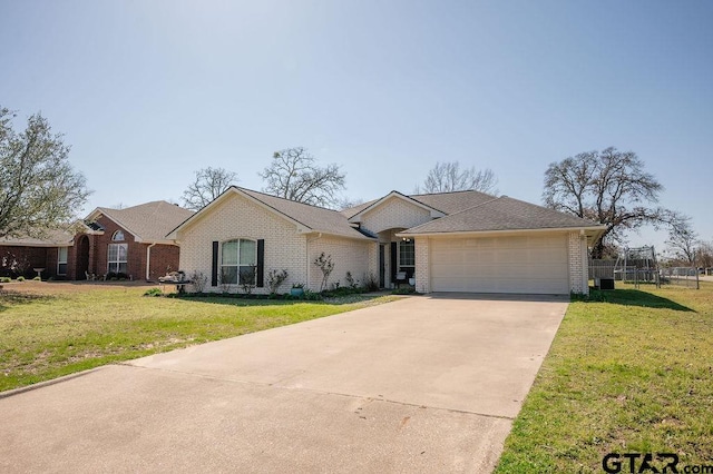 ranch-style house with brick siding, a trampoline, concrete driveway, a front yard, and an attached garage