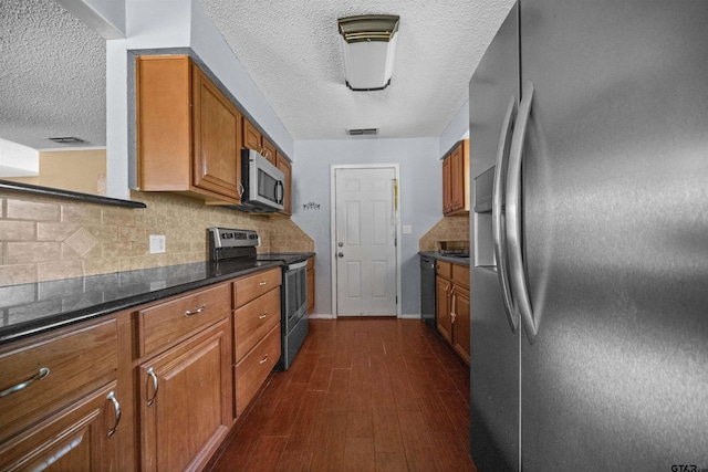 17607 Kristopher Cir, Whitehouse, TX 75791 - kitchen with appliances with stainless steel finishes, a textured ceiling, brown cabinets, and tasteful backsplash