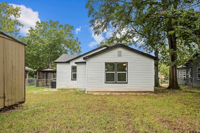 back of house with a lawn and central AC