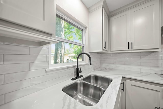 kitchen featuring white cabinetry, light stone counters, tasteful backsplash, and sink