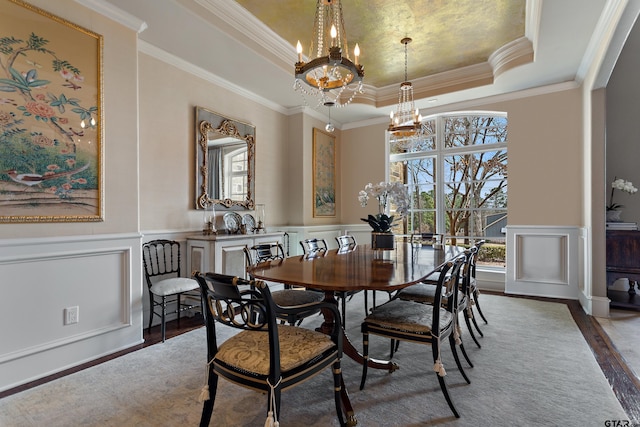 dining room with a tray ceiling, a notable chandelier, a decorative wall, and wood finished floors