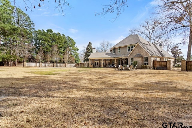 view of front facade with a front lawn, a chimney, fence, and brick siding