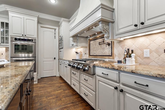 kitchen with stainless steel appliances, premium range hood, ornamental molding, and light stone counters