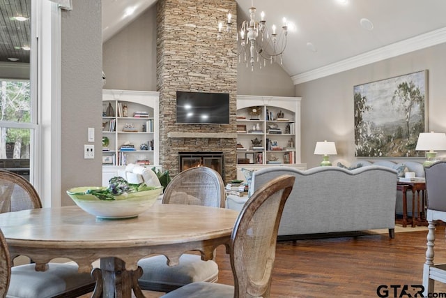 dining area featuring high vaulted ceiling, ornamental molding, a stone fireplace, wood finished floors, and a chandelier