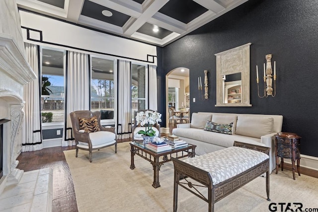 living room with arched walkways, light wood finished floors, beam ceiling, and baseboards