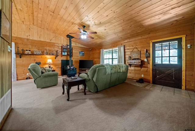 225 Springwood Cir, Chandler, TX 75758 - living room featuring a wood stove, wooden walls, vaulted ceiling, carpet floors, and a ceiling fan