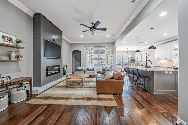 204 Providence Pl, Bullard, TX 75757 - living room featuring dark wood-type flooring, ceiling fan, arched walkways, a fireplace, and ornamental molding