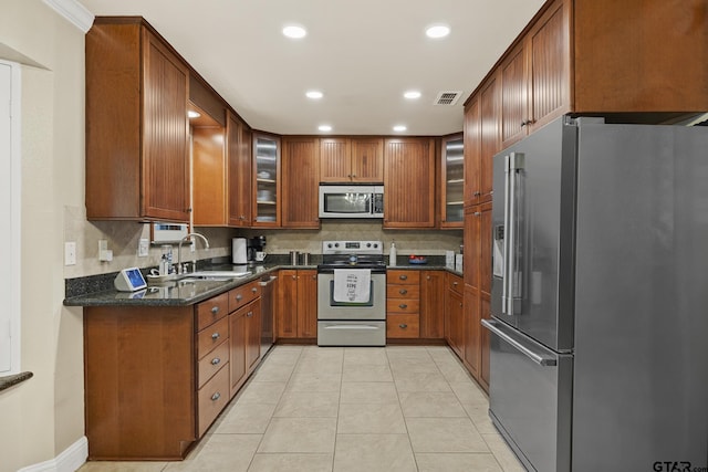 5298 Leaning Oaks Dr, Flint, TX 75762 - kitchen with appliances with stainless steel finishes, a sink, brown cabinetry, backsplash, and glass insert cabinets