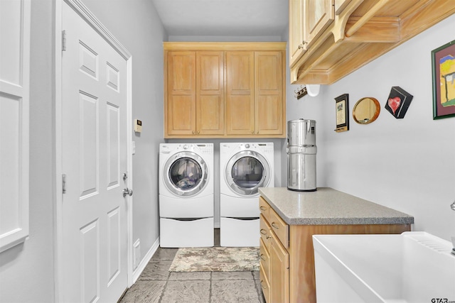 clothes washing area with separate washer and dryer and cabinets