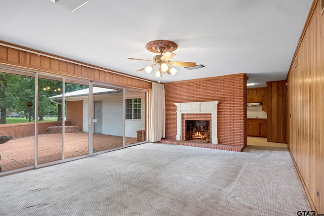 unfurnished living room with wood walls, light colored carpet, and a fireplace