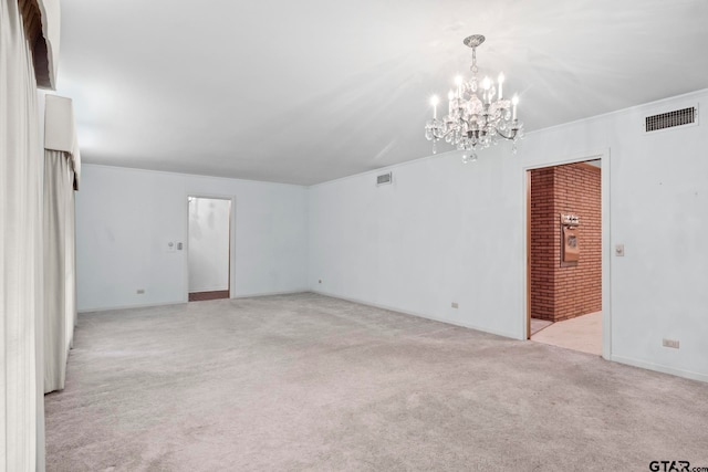 carpeted spare room with an inviting chandelier