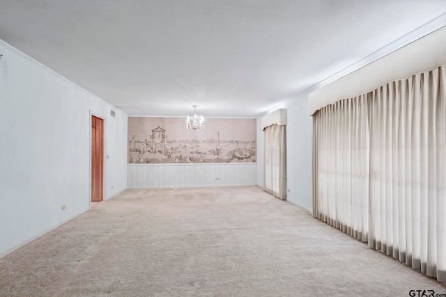 carpeted spare room featuring crown molding and a notable chandelier