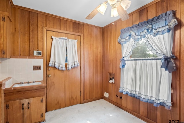 interior space featuring wood walls, ceiling fan, and sink