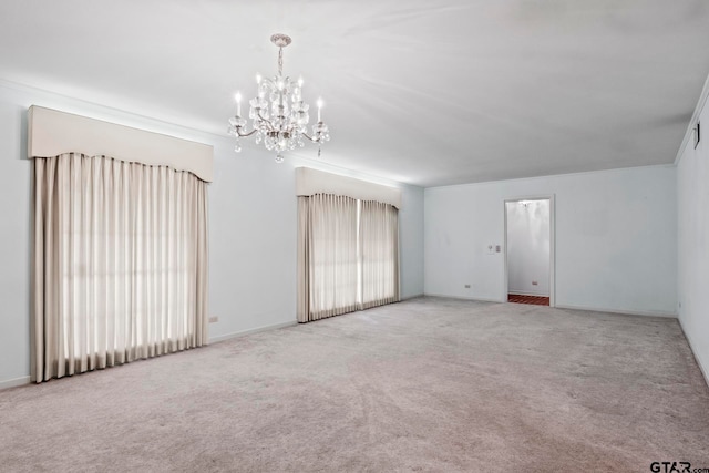 carpeted spare room featuring a wealth of natural light and a notable chandelier