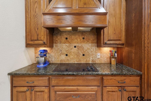 302 Coventry St, Bullard, TX 75757 - kitchen featuring black electric cooktop, premium range hood, tasteful backsplash, brown cabinetry, and dark stone counters
