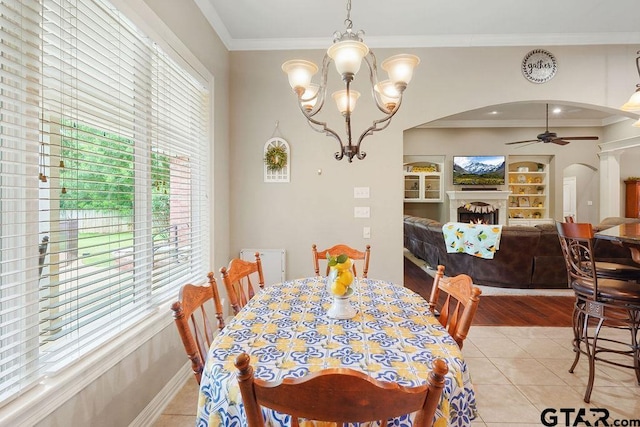 302 Coventry St, Bullard, TX 75757 - dining room with arched walkways, ceiling fan, crown molding, light tile patterned floors, and a warm lit fireplace