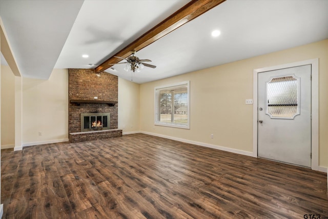 unfurnished living room featuring a brick fireplace, dark hardwood / wood-style flooring, ceiling fan, and lofted ceiling with beams