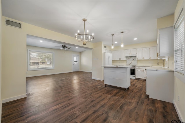 kitchen featuring white refrigerator, pendant lighting, ceiling fan with notable chandelier, white cabinets, and sink