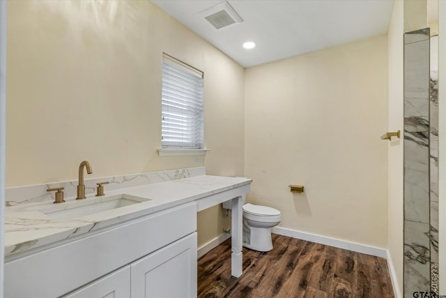 bathroom with toilet, vanity, and wood-type flooring